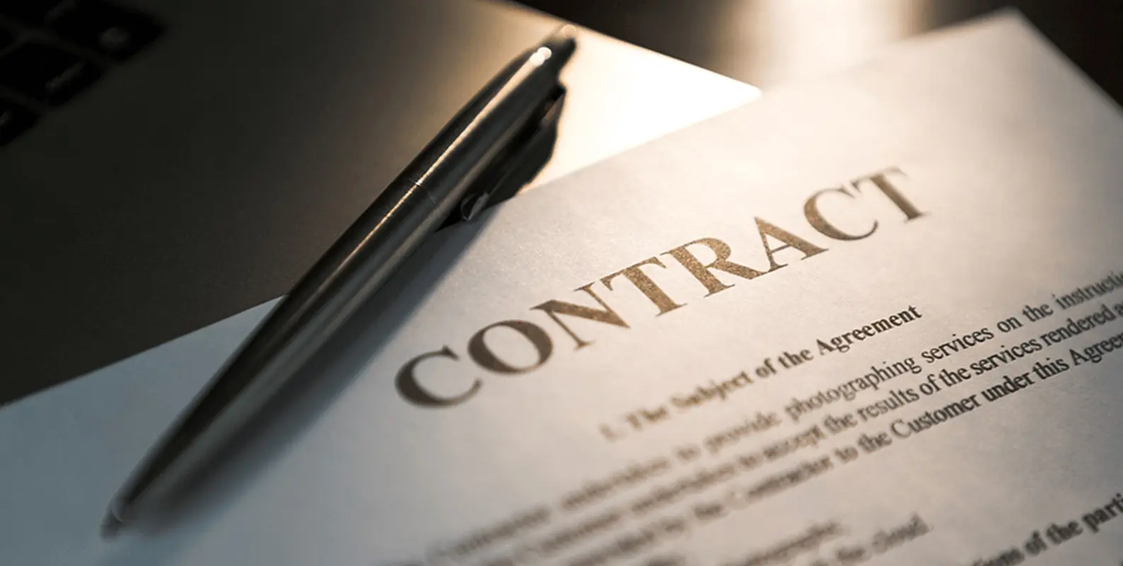 Close-up of a contract document with 'CONTRACT' in bold and a pen nearby.